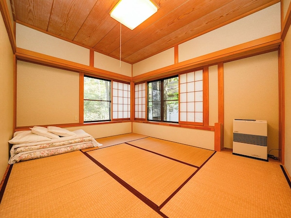 A traditional Japanese room with tatami flooring, shoji screens, and a futon bed.