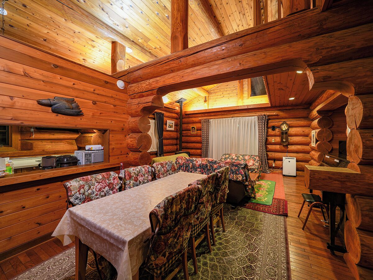 Ein Blockhaus-Interieur mit Essbereich, Kamin und einer gemütlichen Sitzecke.