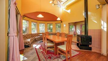 A cozy room with a wooden dining table, chairs, a sofa, and a large window.