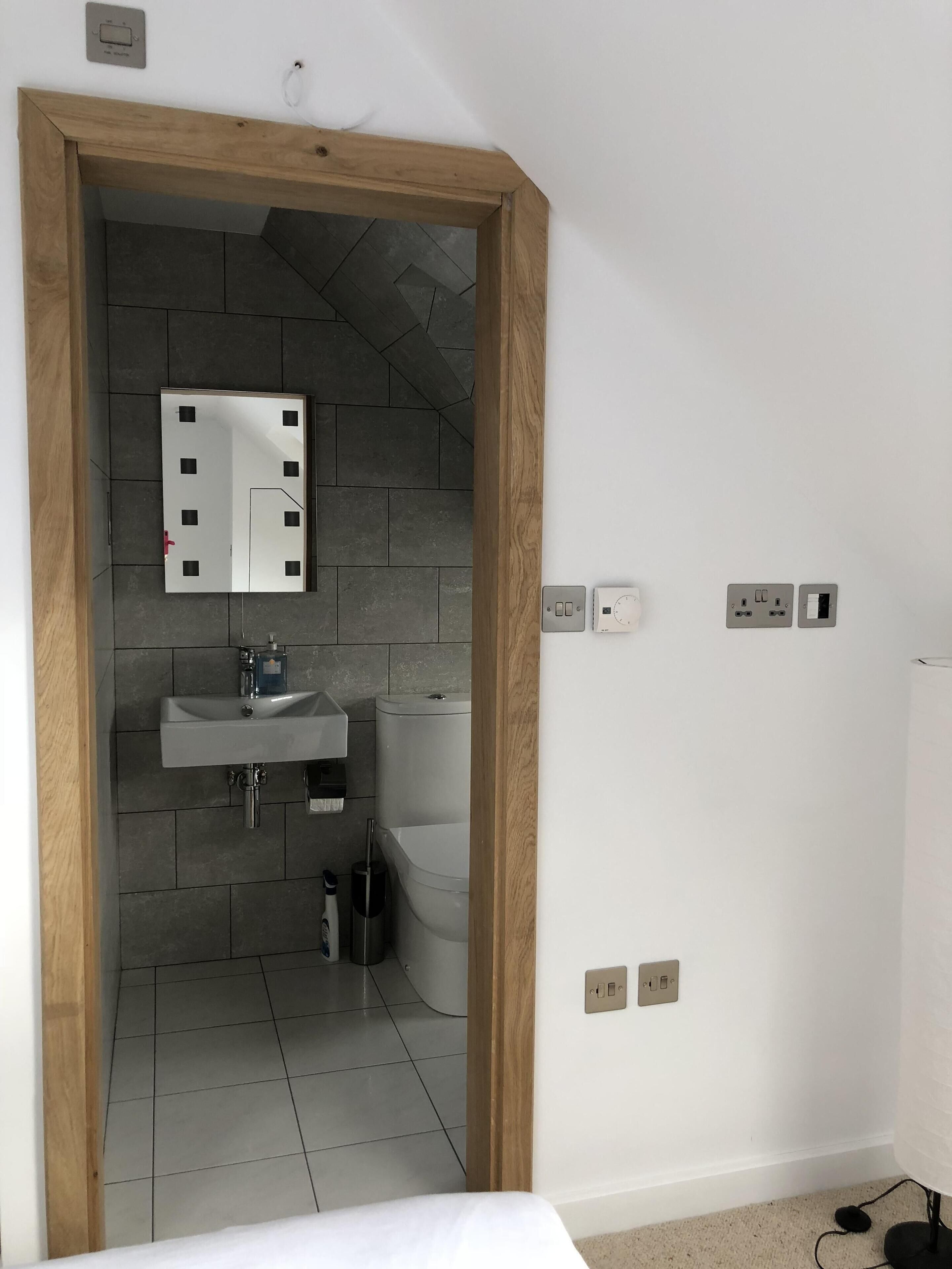 Un baño moderno con un marco de madera, un espejo, un lavamanos y un inodoro.