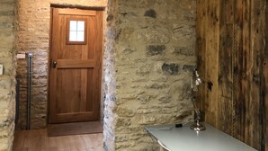 A rustic room with a stone wall, wooden door, and a desk with a lamp. - Beautiful self contained Cotswold style cottage 15 mins Central Oxford (Cassington)