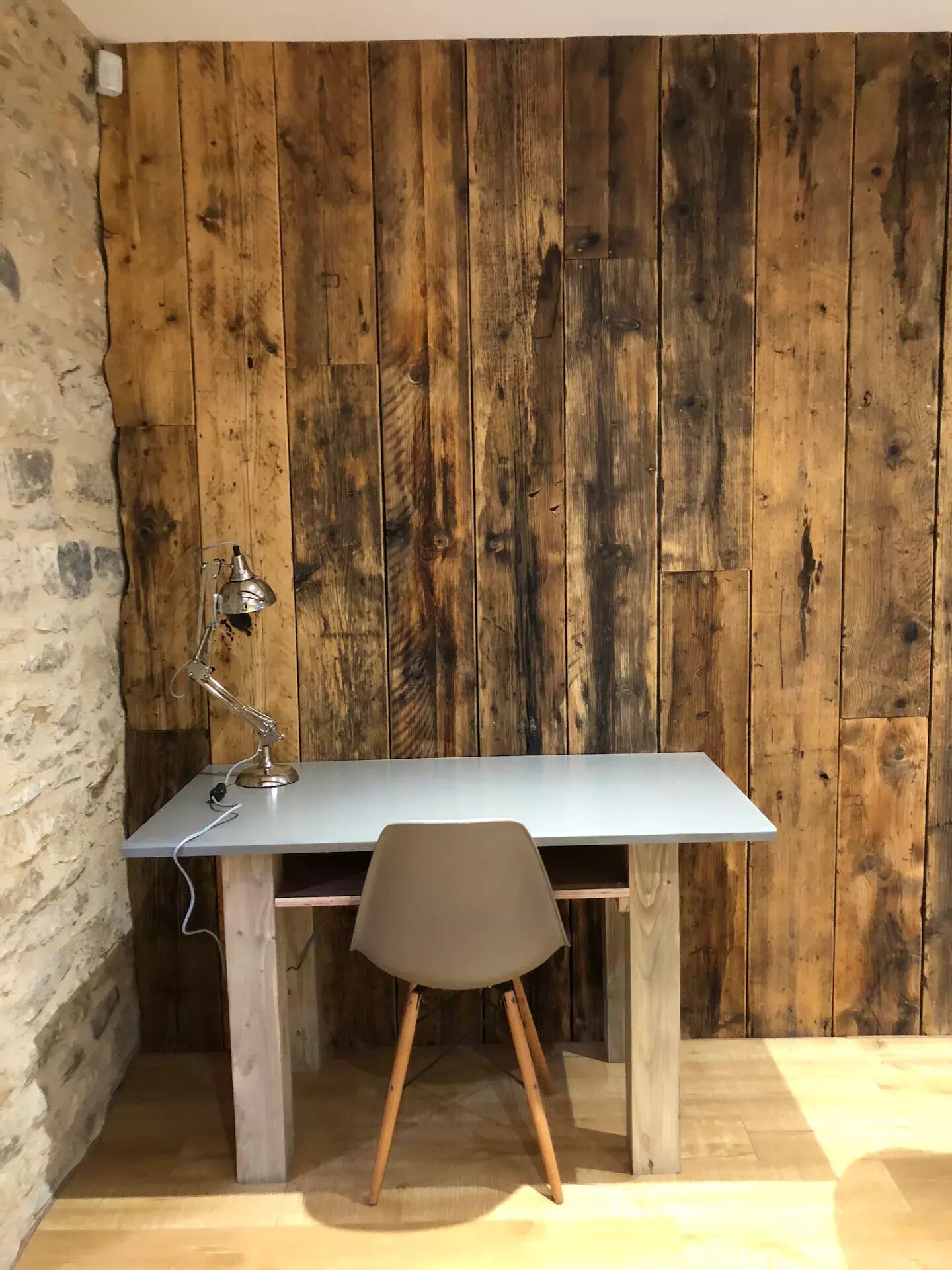 A workspace with a wooden wall, a desk, and a chair.