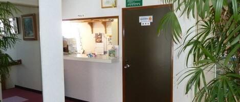 A reception area with a reception desk, a closed door with a sign, and a potted plant.