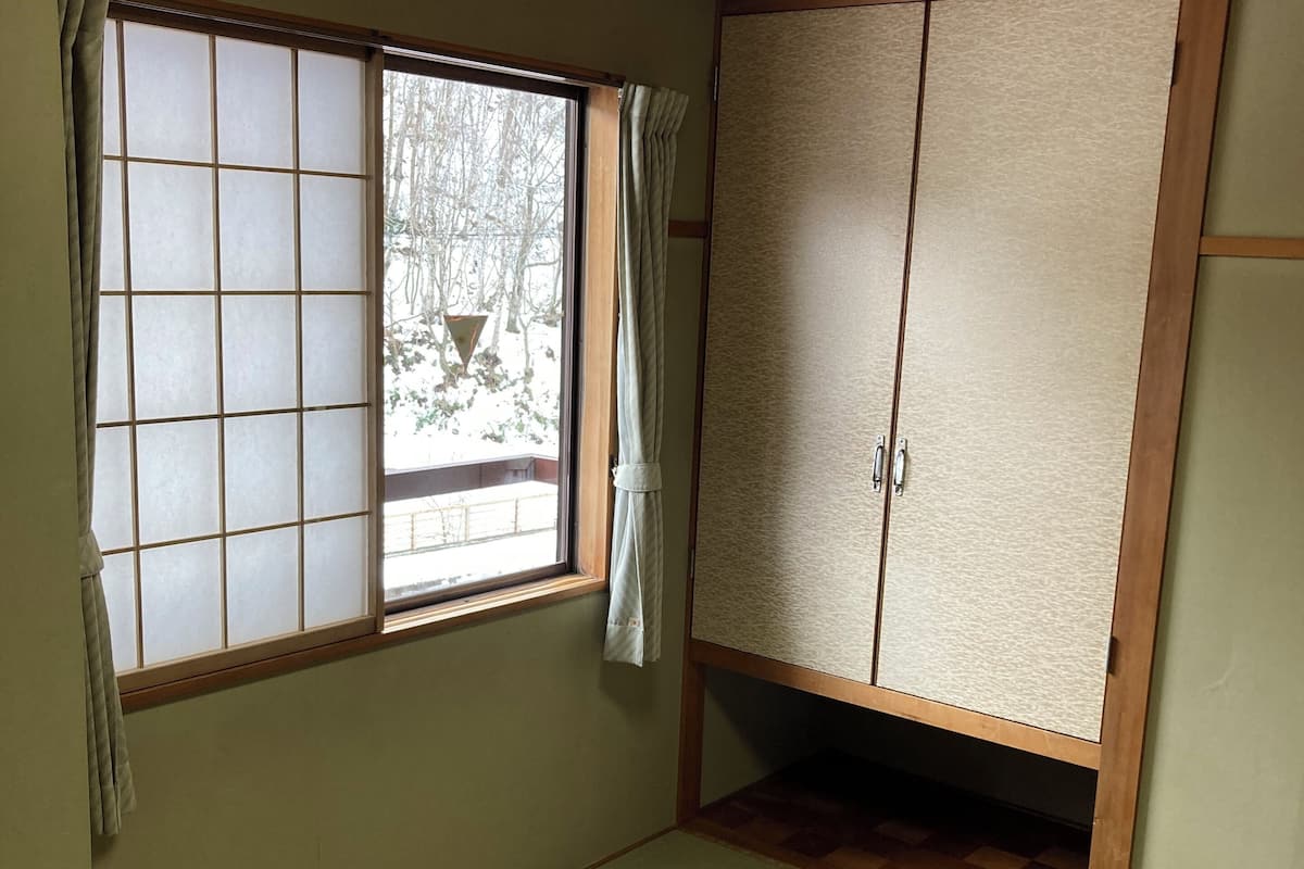 A room with tatami flooring, a sliding shoji screen, a wardrobe, and a ceiling fan.