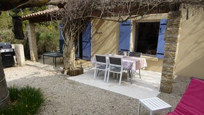 Un espace extérieur aménagé avec une table et des chaises, un barbecue et un fauteuil de relaxation.