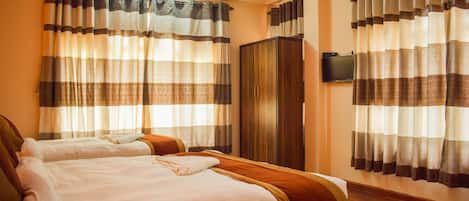 A hotel room with two beds, a wardrobe, and a television on the wall.
