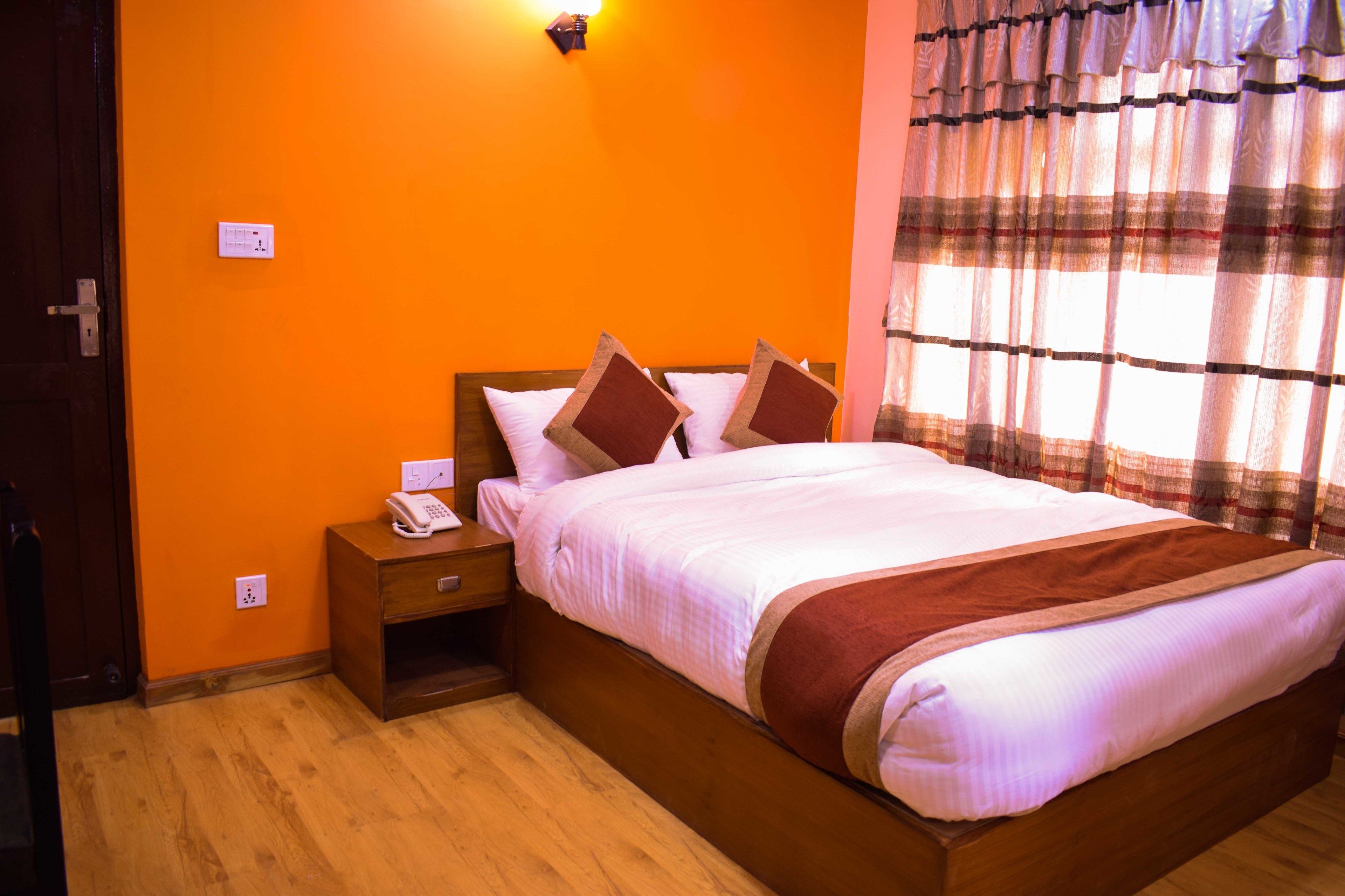 A bedroom with an orange wall, a wooden bed, a nightstand, and a window with curtains.