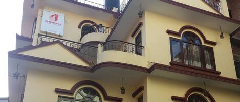 A multi-story building with a balcony on the second floor, a sign indicating it is a 'Peace Home', and a water tank on the roof.