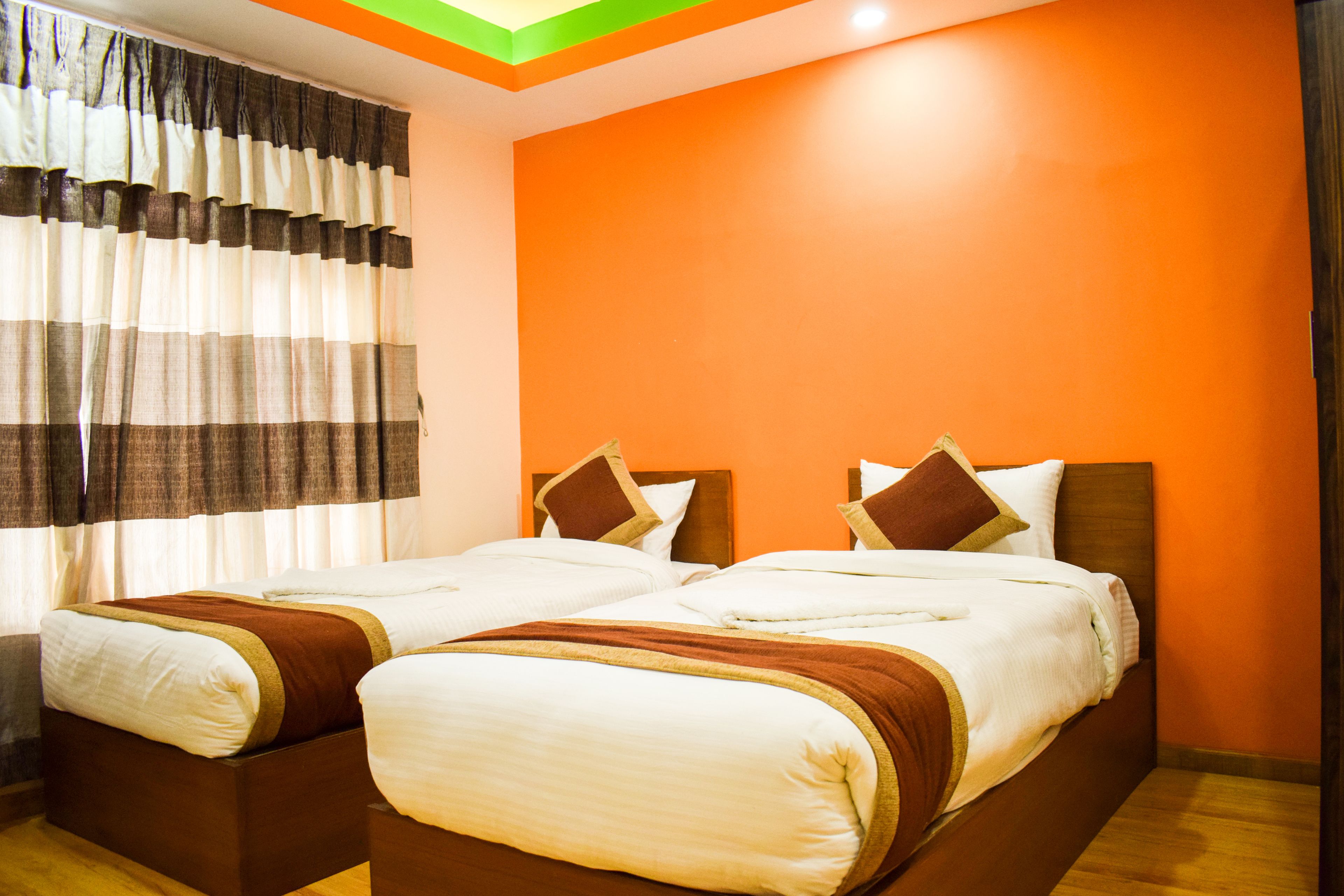 A hotel room with two beds, orange walls, and a wooden floor.