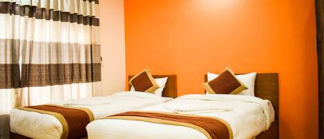 Habitación de hotel con dos camas, paredes anaranjadas y suelo de madera.