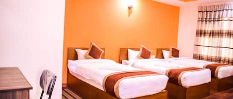 A hotel room with two wooden beds, a desk, and a chair.
