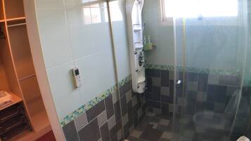 Un baño con cabina de ducha de cristal, un lavabo blanco y suelo de baldosas.