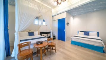 Un dormitorio con dos camas, una mesita con sillas y una cama con dosel.