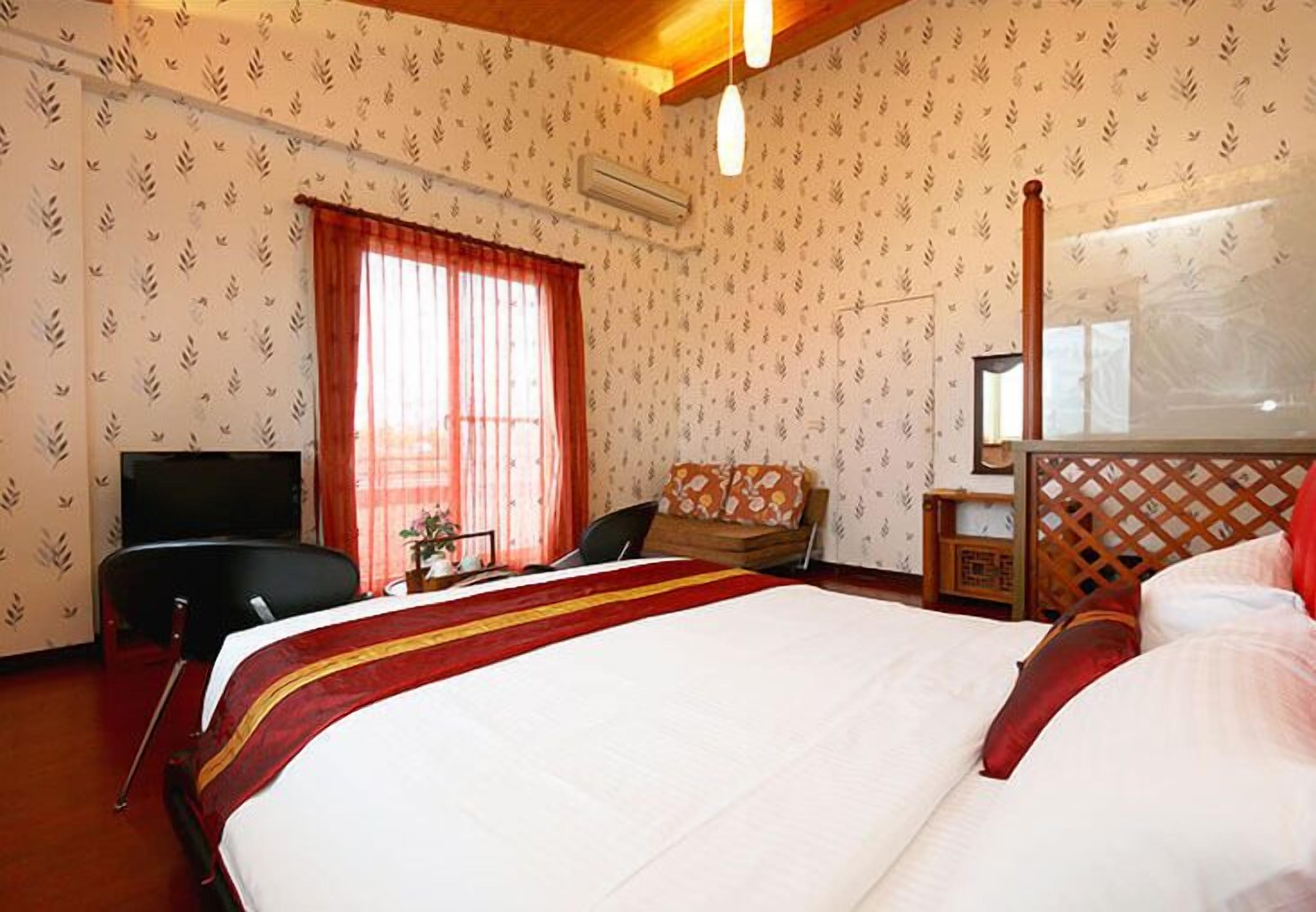 Habitación de hotel con una cama grande, un escritorio con silla, televisión y ventana con cortinas.