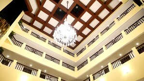 A multi-level hotel interior with a central chandelier, balconies, and a modern ceiling design.