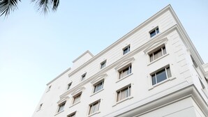 A multi-story white building with a symmetrical facade, multiple windows, and a flat roof.