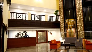 A lobby with a reception desk, seating area, and a staircase.