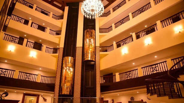 A multi-story hotel lobby with a central atrium, a grand chandelier, and a spiral staircase.