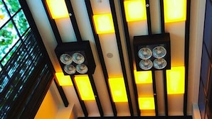 Un interior moderno con un diseño geométrico en el techo que incluye iluminación empotrada.