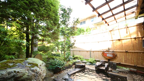 A traditional Japanese garden with a koi pond, wooden bridge, and bamboo fence. - Yudanaka Yumoto (Yamanouchi)