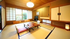 A traditional Japanese room with tatami flooring, a low table with cushions, a television, and sliding doors. - Yudanaka Yumoto (Yamanouchi)
