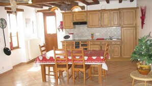 Una cocina con armarios de madera, suelo de baldosas y una mesa de comedor con sillas.
