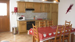 Una cocina con armarios de madera, microondas, estufa y una mesa de comedor con sillas.