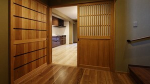 Um corredor interno de madeira com uma porta deslizante que dá para uma cozinha.