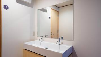 A modern bathroom with a white sink and a large mirror.