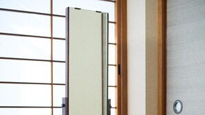 A traditional Japanese room with tatami flooring, a sliding shoji screen, and a wooden cabinet with a mirror. - Ito Ryokan (Tokyo)