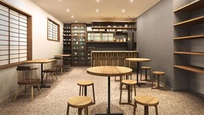 A modern interior with round tables and chairs, a kitchen area with shelves, and a view through a shoji screen. - Ito Ryokan (Tokyo)