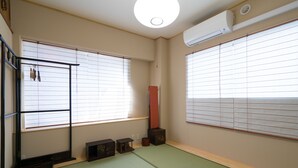 A traditional Japanese room with tatami flooring, sliding shoji doors, and a tatami mat storage box. - Ito Ryokan (Tokyo)