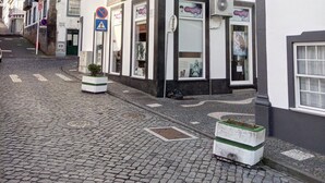 A cobblestone street with a white building featuring multiple windows and a sign for 'Engina'. - Janelas da Praia, Apartment by the beach. (Praia da Vitória)