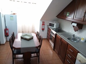 Eine Küche mit Esstisch, Stühlen, einer Mikrowelle, einem Backofen, einer Spüle und einem Feuerlöscher.
