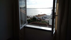 A room with a large window overlooking a coastal view. - Janelas da Praia, Apartment by the beach. (Praia da Vitória)
