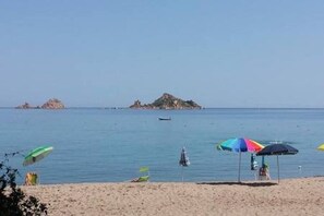 Una platja amb ombrelles i un vaixell a l'aigua.