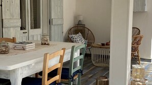 A dining area with a white table, wooden chairs, wicker chairs, and a patterned floor. - Apartment 20 meters from the sea (Tancau sul mare)
