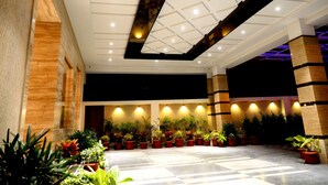 A spacious indoor area with a high ceiling, recessed lighting, and a variety of potted plants arranged along the walls. - ASR Parklane, A Bergamont Hotel - Hosur (Hosur)