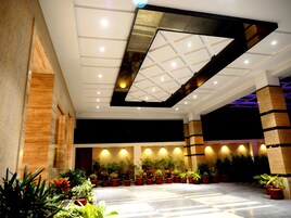 Un espacio interior amplio con techo alto, iluminación empotrada y una variedad de plantas en macetas dispuestas a lo largo de las paredes.