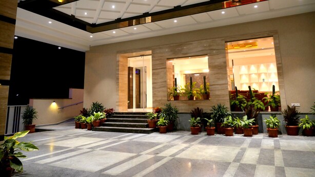 A spacious lobby with a checkered floor, a staircase leading to an upper level, and multiple potted plants. - ASR Parklane, A Bergamont Hotel - Hosur (Hosur)