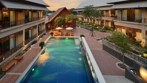 Un hotel con piscina central, varios balcones y zonas de estar al aire libre.