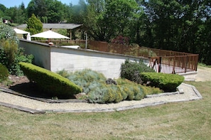 A garden with a stone wall, wooden fence, and various plants.
