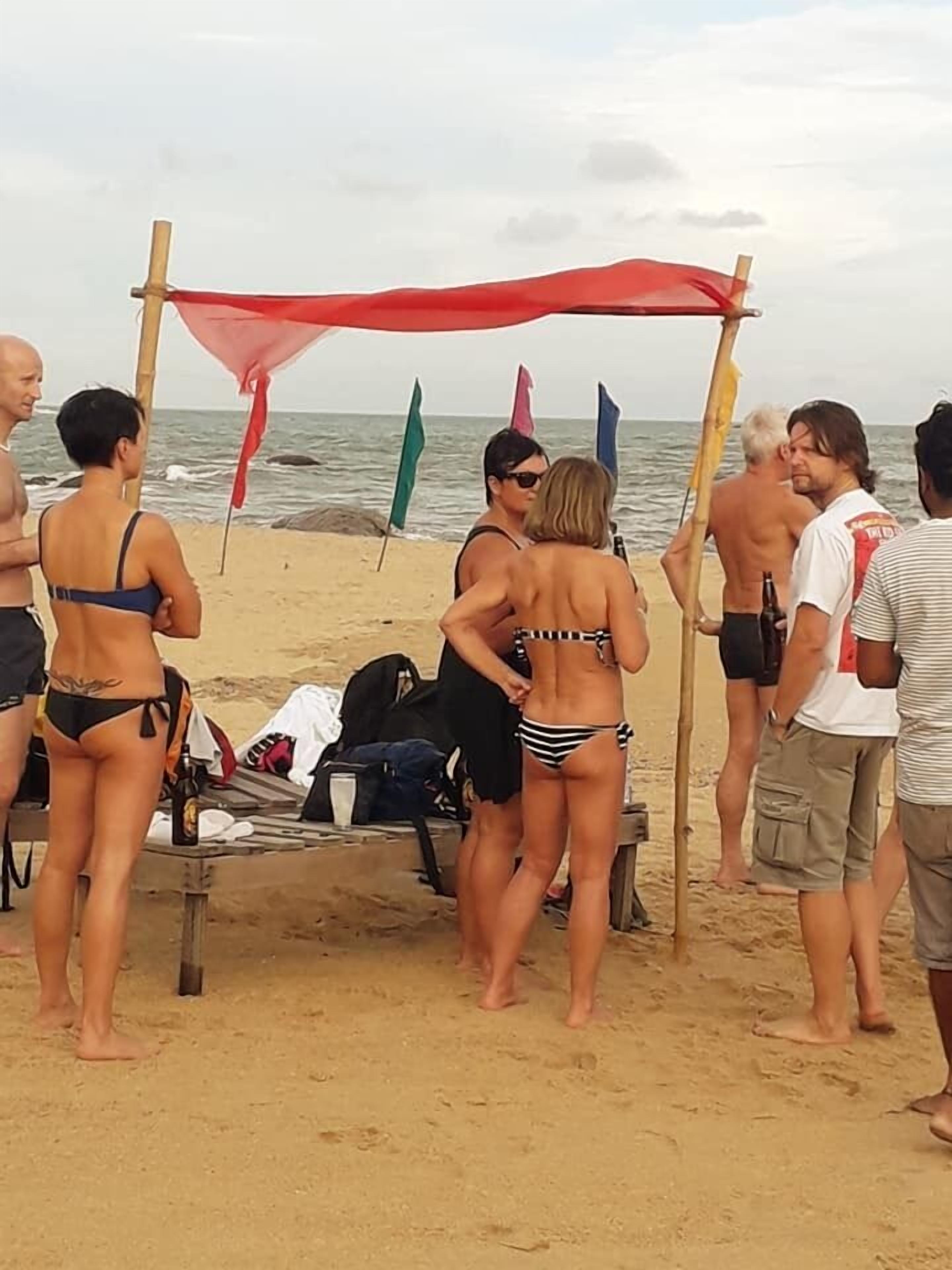 A beach scene with people in swimwear and a red canopy structure.