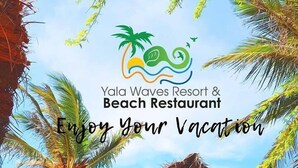 Een houten gebouw met rieten dak, omgeven door palmbomen, aangeduid als Yala Waves Resort & Beach Restaurant.
