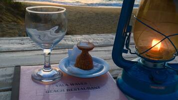 Una mesa con un menú, un vaso y un farol junto al mar.