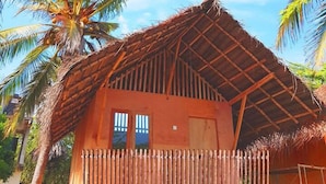 Een houten huis met rieten dak, een balkon en een raam.