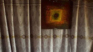 Een hotelkamer met een bed, twee blauwe kussens, een handdoekarrangement in de vorm van een hart, en behang met een patroon.