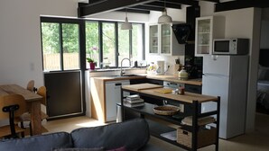 Una cocina compacta con comedor, sofá y un amplio ventanal que proporciona luz natural.
