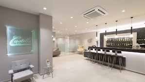 A modern hotel lobby with a bar area, seating, and a glass wall with a neon sign. - Castello Hotel (Patras)