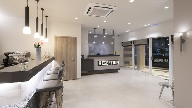 A modern reception area with a counter, bar stools, and a reception desk. - Castello Hotel (Patras)